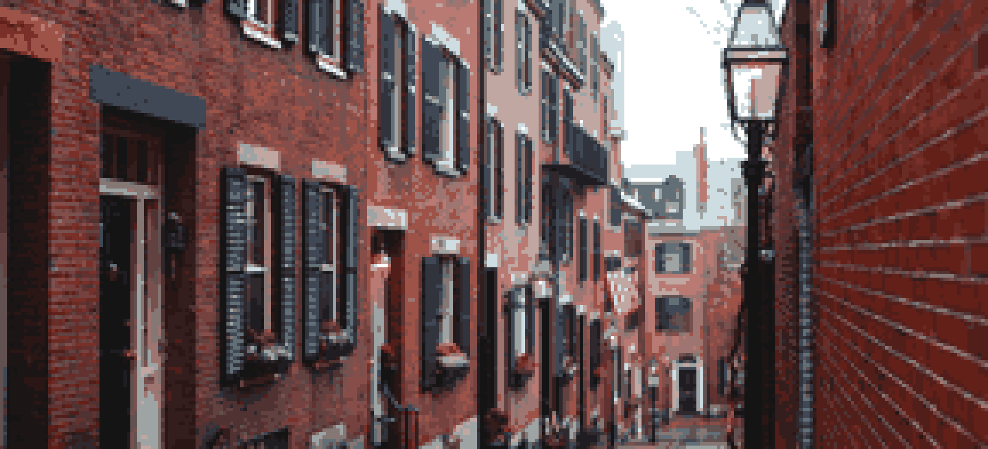 Acorn Street on Beacon Hill: a narrow cobblestone lane between brick row houses with black shutters and a gas lamp.